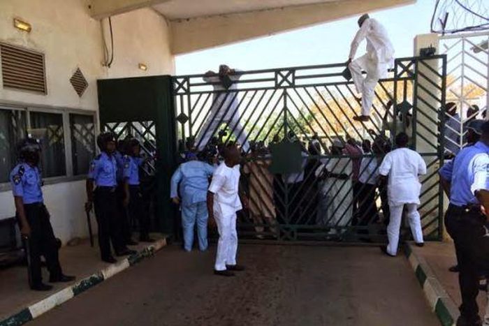 Legislators scaling the fence of the National Assembly complex