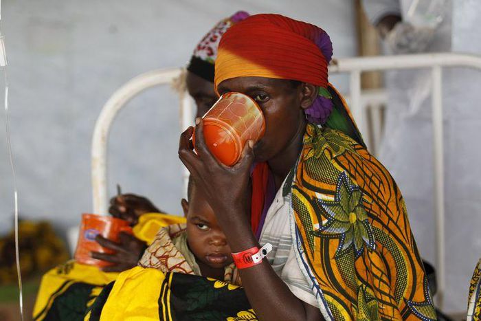 A Burundian refugee woman carries her child as she drinks from a cup at a makeshift clinic at the Lake Tanganyika stadium in Kigoma western Tanzania, May 19, 2015.    REUTERS/Thomas Mukoya
