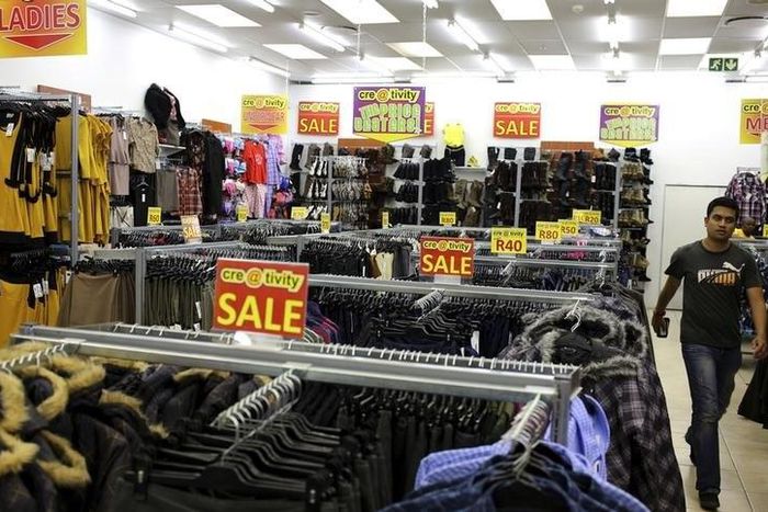 A shopper walks past sale signs at a shopping centre in Lenasia, south of Johannesburg, August 28, 2013.   REUTERS/Siphiwe Sibeko