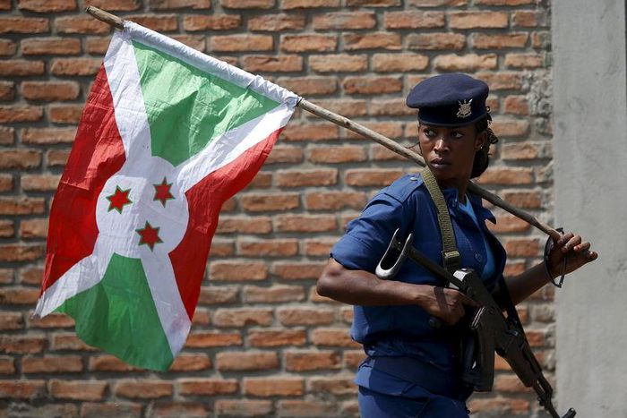A policewoman carries a Burundi flag during a protest against President Pierre Nkurunziza's decision to run for a third term in Bujumbura, Burundi, May 29, 2015. REUTERS/Goran Tomasevic
