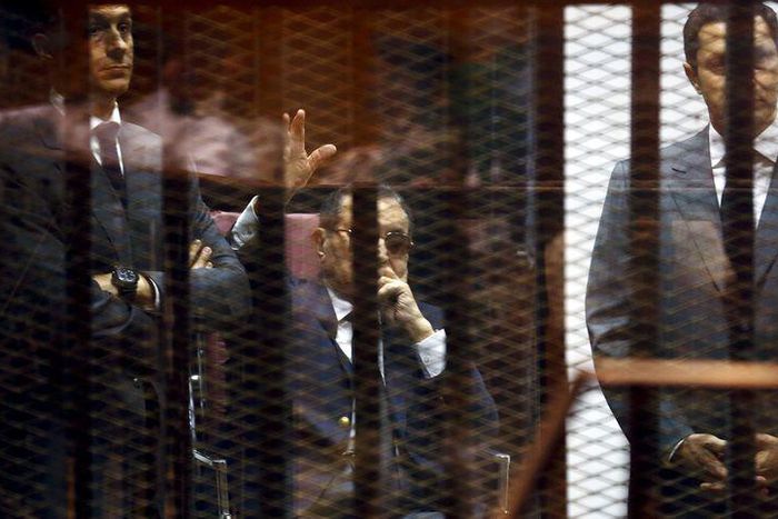 Egypt's former president Hosni Mubarak waves to his supporters with his sons Gamal (L) and Alaa (R) inside a cage in a courtroom during them trial at the police academy, on the outskirts of Cairo, May 9, 2015. An Egyptian court sentenced former preside...