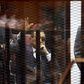 Egypt's former president Hosni Mubarak waves to his supporters with his sons Gamal (L) and Alaa (R) inside a cage in a courtroom during them trial at the police academy, on the outskirts of Cairo, May 9, 2015. An Egyptian court sentenced former preside...