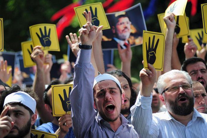 Pro-Islamist demonstrators shout slogans in favour of former Egyptian President Mohamed Mursi and hold signs that show the Rabaa hand gesture, which symbolizes support for the Muslim Brotherhood, during a rally in front of the Haghia Sophia museum at S...