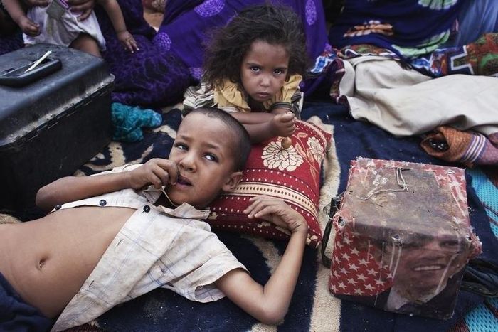 Elah, 7, (L) and Tahye Iselkou, 5, lie next to a box draped with a picture of U.S. President Barack Obama on the floor of their shelter at Mbera refugee camp in southern Mauritania, May 24, 2012. REUTERS/Joe Penney