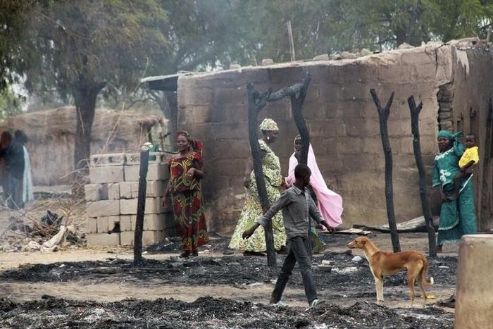 People stand near burnt structures in the aftermath of what Nigerian authorities said was heavy fighting between security forces and Islamist militants in Baga, a fishing town on the shores of Lake Chad, adjacent to the Chadian border, in a file photo....