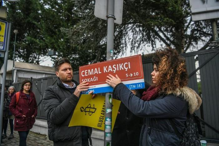 Members of Amnesty International hang a sign reading "Jamal Khashoggi Street" where the Saudi Arabian consulate is located in Istanbul, during a ceremony marking 100 days since the murder of the journalist there
