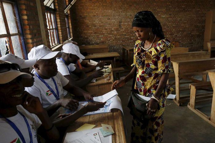 A woman receives ballot papers from election officials at a voting station in Burundi's capital Bujumbura during the country's presidential elections, July 21, 2015. REUTERS/Mike Hutchings