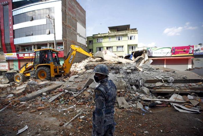 An armed police personnel looking for survivors stands in front of a collapsed house after the earthquake in Kathmandu May 12, 2015.  REUTERS/Navesh Chitrakar