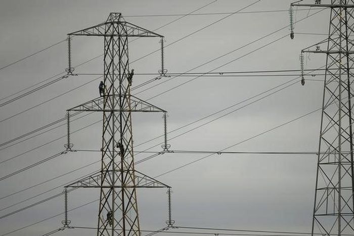 Workers paint an electricity pylon near Lymm, northern England February 18, 2015.   REUTERS/Phil Noble