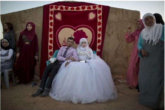 Ahmad Khalid and his bride, Fatheya Mohammed, both 21, sit in front of his family's tent during their wedding ceremony in an informal tent settlement on the outskirts of Mafraq, Jordan, near the Syrian border, on Aug. 7.