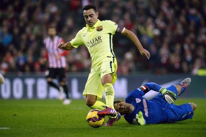 Barcelona's Xavi Hernandez passes Athletic Bilbao goalkeeper Gorka Iraioz during their Spanish first division soccer match at San Mames stadium in Bilbao, February 8, 2015. REUTERS/Vincent West