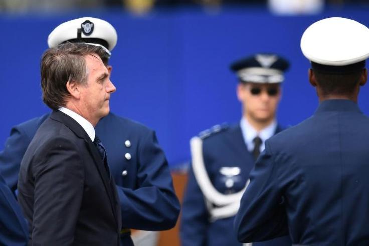 Brazilian President Jair Bolsonaro, seen here receiving military honors at an air base in Brasilia, has deployed the military to fight crime in the northern state of Ceara, scene of attacks by rampaging gangs