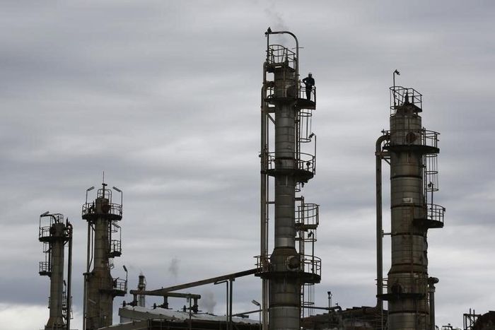 A worker is pictured atop one of several chimneys at Sydney's Caltex Oil refinery in Kurnell, October 14, 2014, after the completion of shutting down of the refinery and its transition to an oil storage facility. REUTERS/Jason Reed