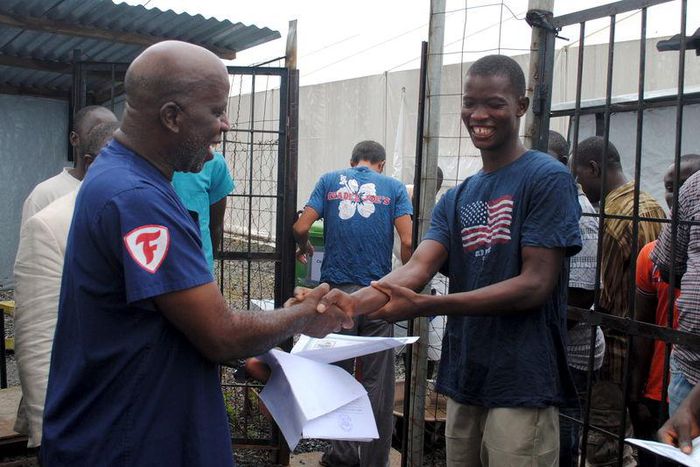 Cassius Kollie (R), 24, one of four people discharged on Monday from an Ebola treatment unit, receives a certificate for being cured of the disease in Paynesville, Liberia, July 20, 2015. REUTERS/James Giahyue