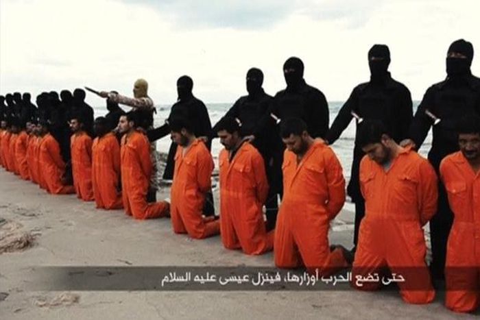 Men in orange jumpsuits purported to be Egyptian Christians held captive by the Islamic State (IS) kneel in front of armed men along a beach said to be near Tripoli, in this still image from an undated video made available on social media on February 1...