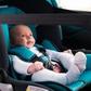 A baby strapped into a car seat, inside a car