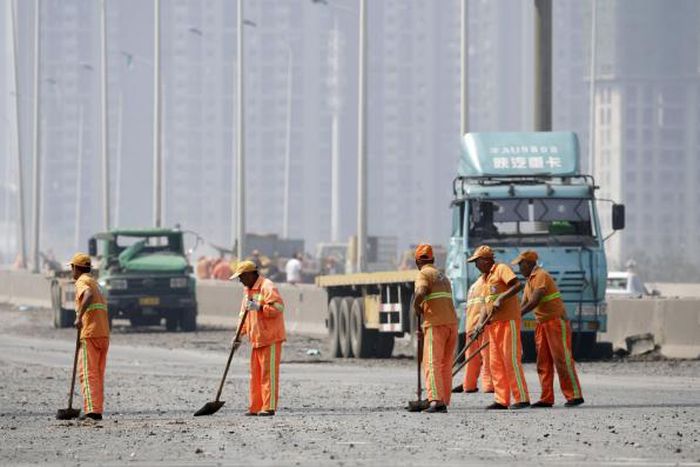 Workers clean debris on a highway near the site of the explosions
