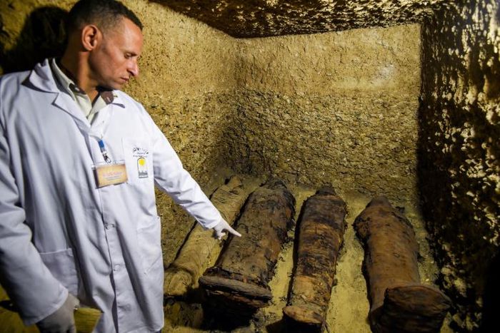 An archaeologist displays mummies laying in burial chambers dating to the Ptolemaic era (323-30 BC), in Egypt's Minya province on February 2, 2019