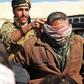 A suspected Islamic State (IS) group fighter who fled from the frontline Syrian village of Baghouz, near the Iraqi border, sits blindfolded in the back of a pickup truck after he was taken into custody by SDF forces for screening