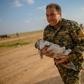 A member of the Kurdish-led Syrian Democratic Forces (SDF) carries a baby followed by a woman who fled the Islamic State (IS) group's last holdout of Baghouz, in northern Syria's Deir Ezzor province