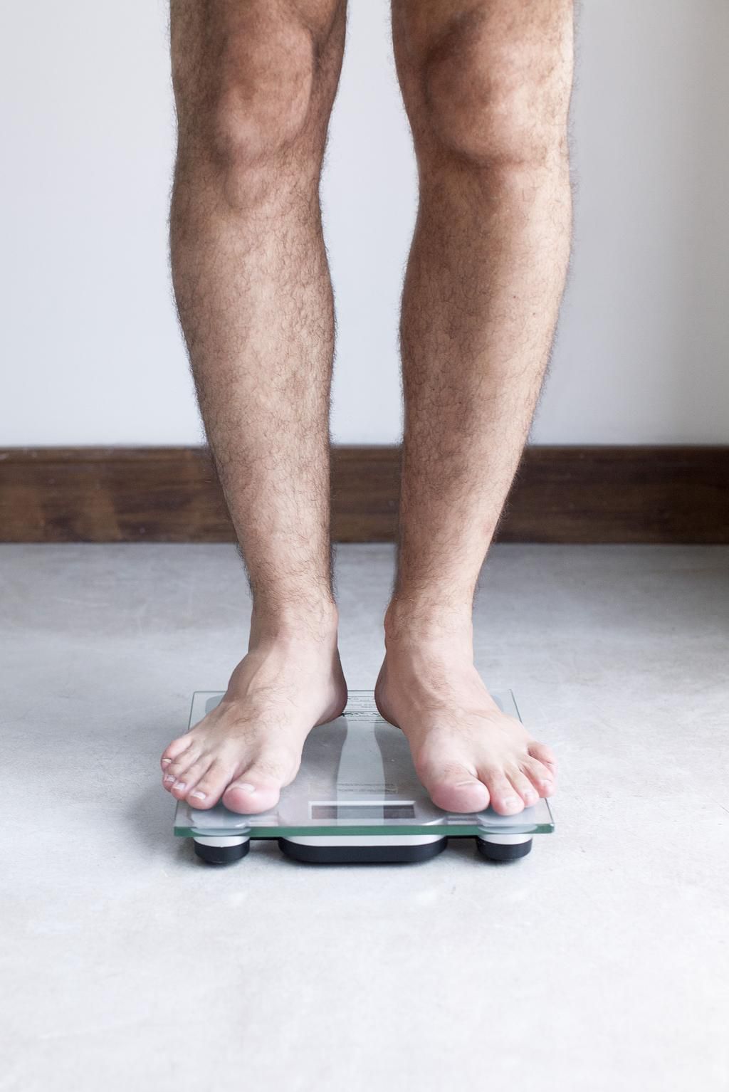 Man weighing self on bathroom scale