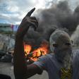 A masked demonstrator gestures before burning tires during protests in Port-au-Prince, on February 10, 2019