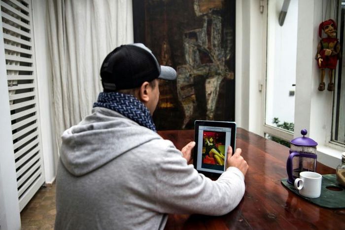 Moroccan Chafik Lafrid looks at a picture of himself on a tablet which went viral, taken after his arrest wearing a dress and a wig