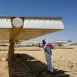 A man talks on his phone under a solar panel on March 29, 2018 in Uyayna, north of Riyadh, where Saudi Arabia is building what is set to be the world's biggest solar plant