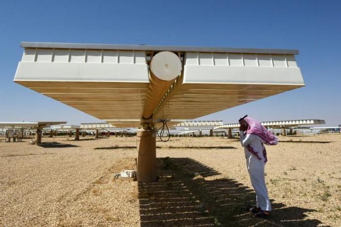 A man talks on his phone under a solar panel on March 29, 2018 in Uyayna, north of Riyadh, where Saudi Arabia is building what is set to be the world's biggest solar plant