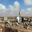 Libyan men walk amidst debris of a destroyed building in the town of Al-Goualiche, 120 kilometres (75 miles) west of the capital Tripoli