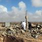 Libyan men walk amidst debris of a destroyed building in the town of Al-Goualiche, 120 kilometres (75 miles) west of the capital Tripoli
