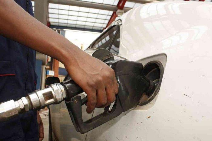 A petrol station attendant fuelling a car