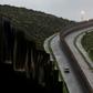 A US Border Patrol vehicle drives near a section of reinforced US-Mexico border fence near Tijuana, Mexico