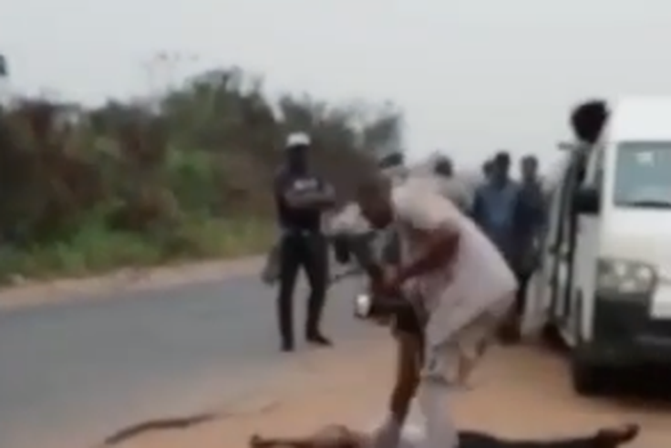 After shooting a traveler dead, a Nigeria Customs Service officer observes his body as if to confirm if he is truly dead.