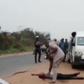 After shooting a traveler dead, a Nigeria Customs Service officer observes his body as if to confirm if he is truly dead.