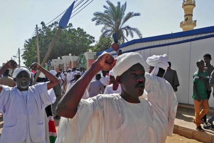 Sudanese men shout slogans during an anti-government protest following Friday noon prayers on January 18, 2019 outside a mosque in Khartoum's twin city Omdurman