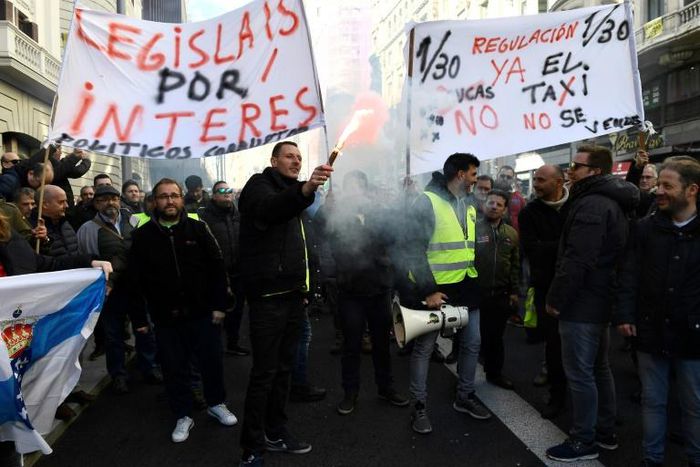 Taxi drivers hold flares and placards reading "Regulation now" during a demonstration in to protest against online ride-sharing services like Uber