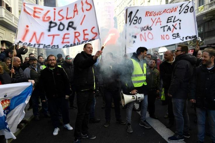 Taxi drivers hold flares and placards reading "Regulation now" during a demonstration in to protest against online ride-sharing services like Uber