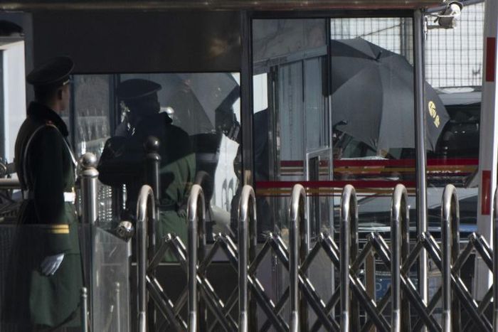 North Korean official Kim Yong Chol is hidden by umbrellas as he arrives at Beijing airport on his way to Washington