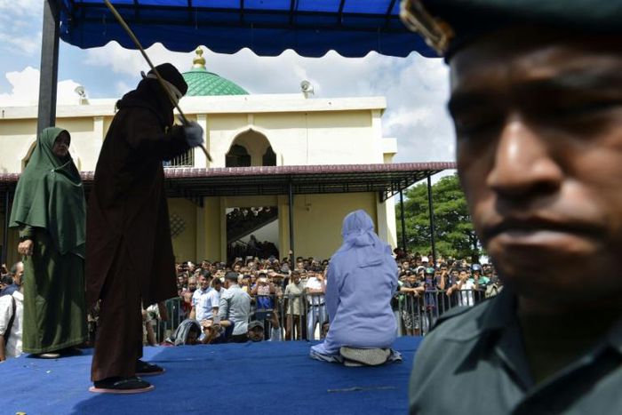 Hundreds watched as an 18-year-old Indonesian woman was flogged outside a mosque in the capital of Aceh province