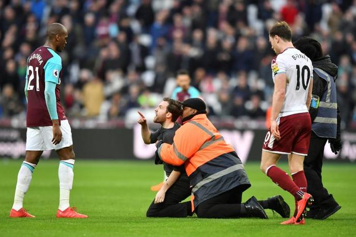 A pitch invader gestures at West Ham United's Angelo Ogbonna (left) during crowd trouble at a Premier League match against Burnley in March