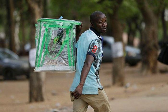 An election official walks away with an empty ballot box at the end of votes count