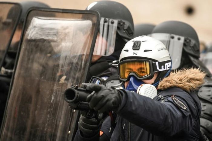 A French police officer aims a "defensive ball launcher" - known by its French initials "LBD" - at protesters during a "yellow vest" demonstration in Paris