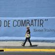 A woman passes graffiti with a partial phrase attributed to Venezuelan President Nicolas Maduro reading "Time to Fight", in Caracas, ahead of competing protests by opposition supporters and regime loyalists