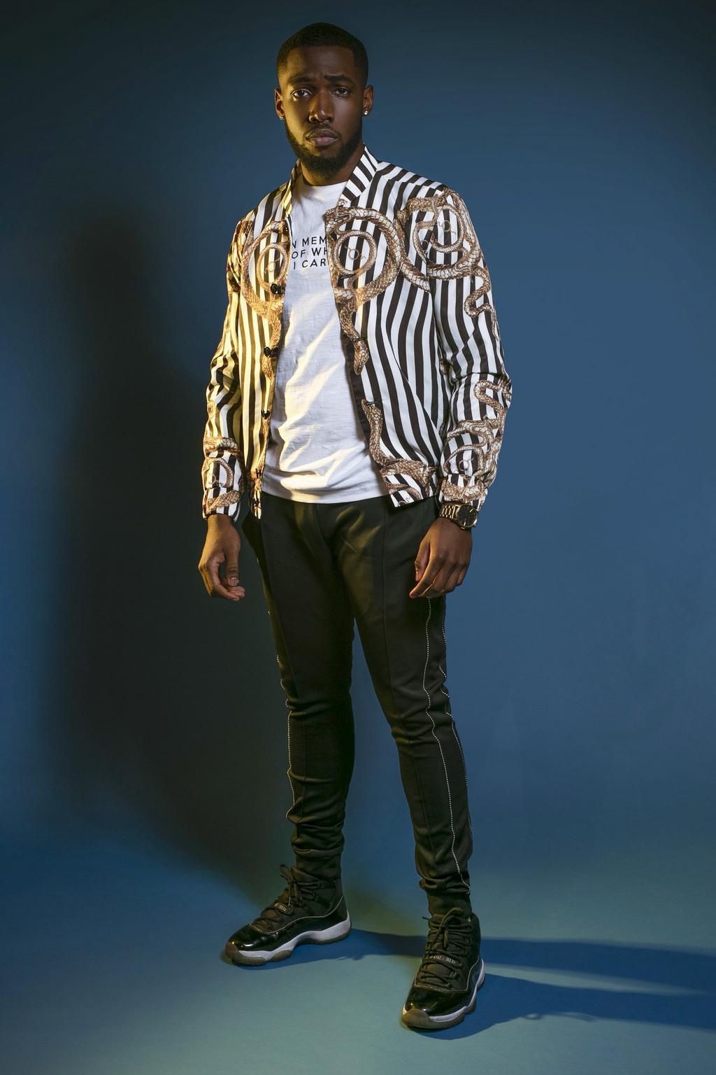 One of the Kupe Boys poses in a chain print bomber jacket for their editorial in Glam Africa magazine