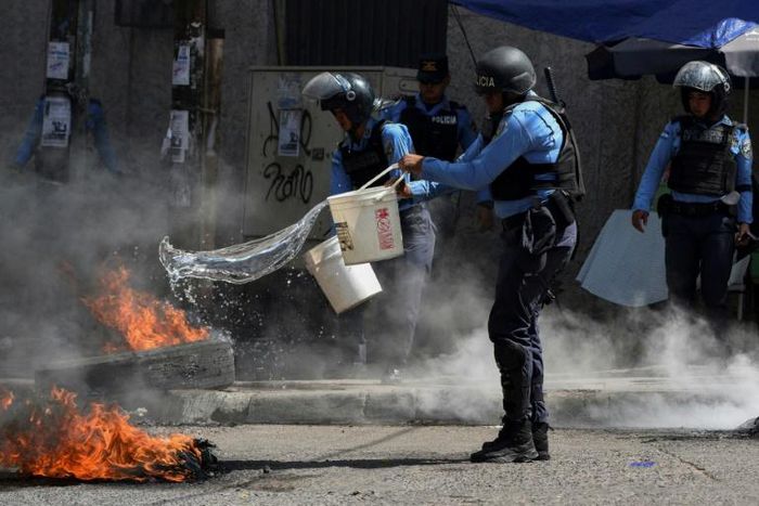 Police try to put out tires set ablaze in a Honduras opposition demonstration on January 27, 2019