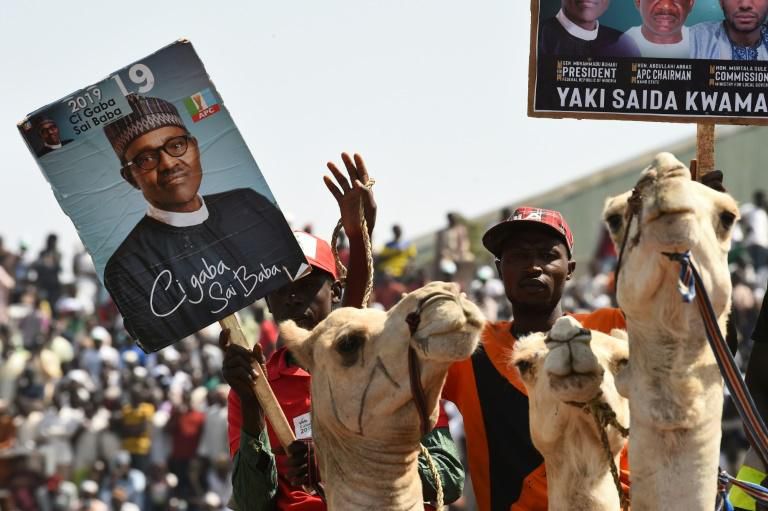 Supporters on camels hold banners of the ruling All Progressives Congress (APC) party during incumbent President Mohammadu Buhari's presidential campaign rally in Kano on January 31, 2019.