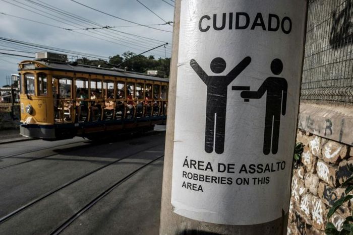 Rio's famous street car passes by a sign warning against robberies on an electricity pole in Santa Teresa, home to favelas where firefights between rival gangs and police are a common sight