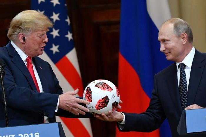 Russia's President Vladimir Putin (R) offers a ball of the 2018 football World Cup to US President Donald Trump after their meeting in Helsinki on July 16, 2018