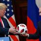 Russia's President Vladimir Putin (R) offers a ball of the 2018 football World Cup to US President Donald Trump after their meeting in Helsinki on July 16, 2018